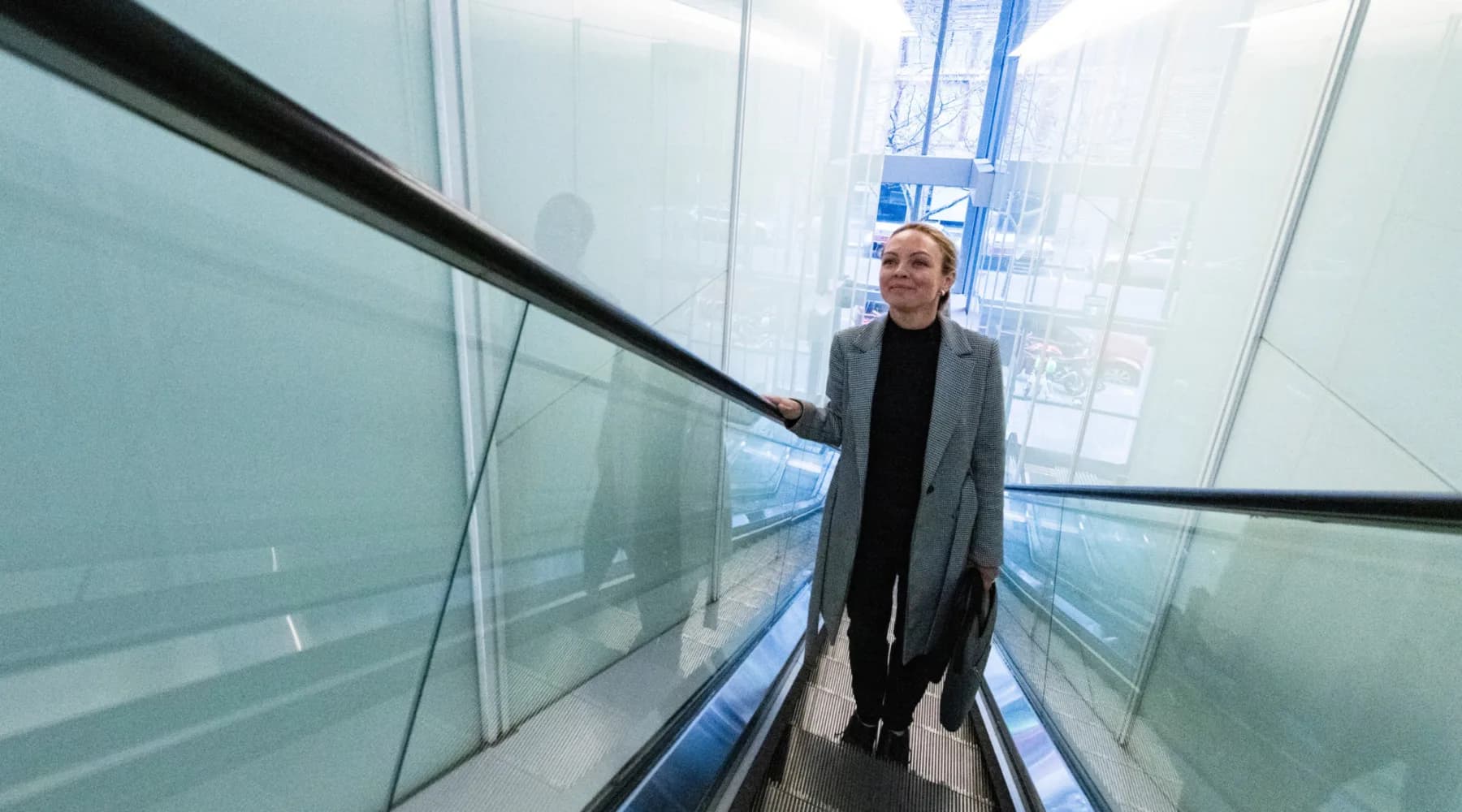 Woman going up escalator in building