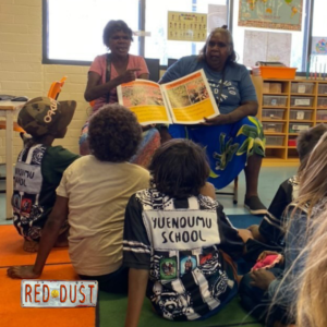 Two indigenous women reading to children